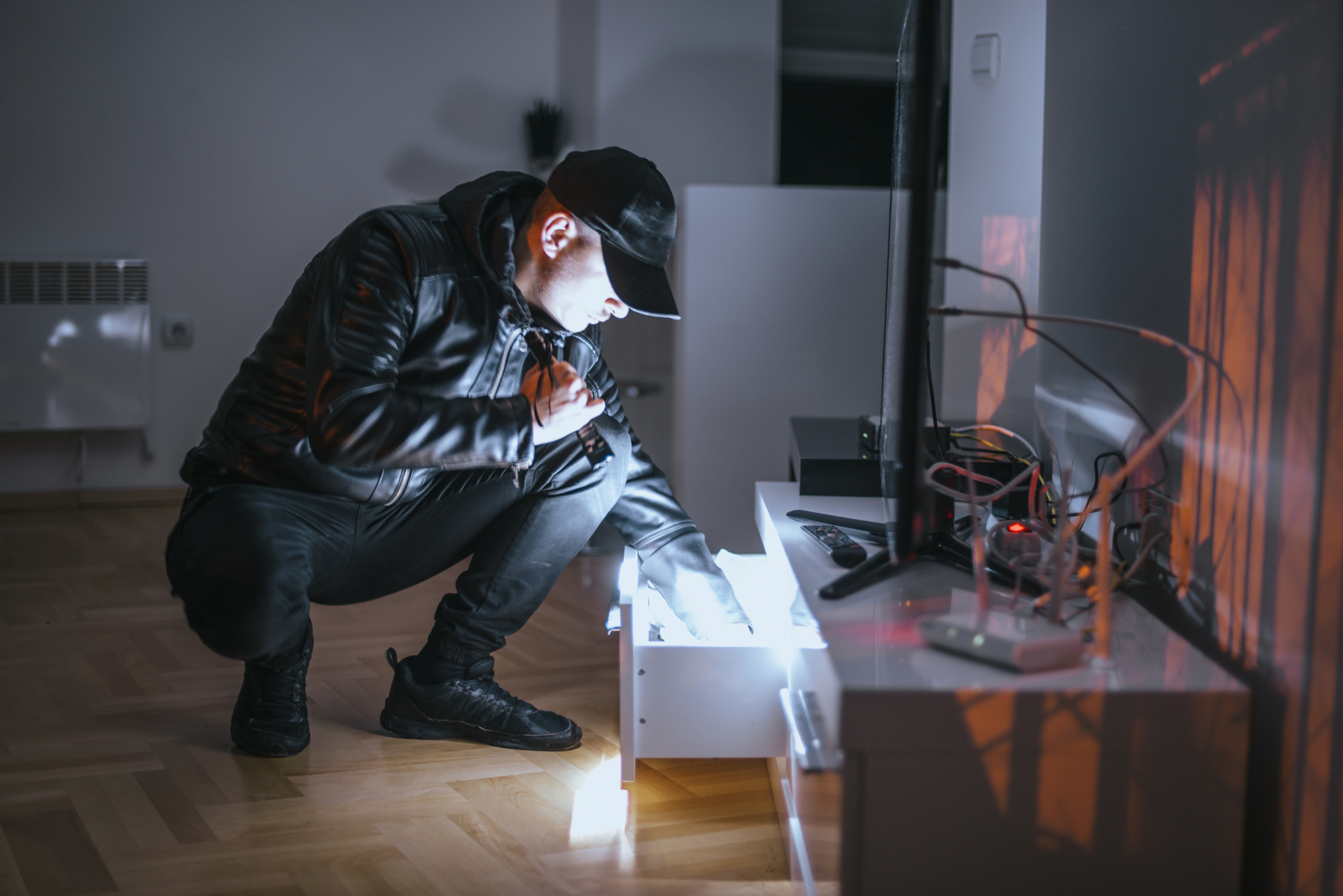 Mann mit Taschenlampe durchsucht Schublade