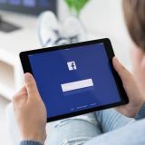 Mann hält ein iPad auf dem der Facebook Login-Bereich zu sehen ist