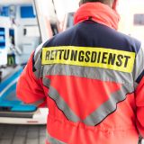 Rückansicht eines Rettungssanitäters, der vor einem geöffneten Krankenwagen steht