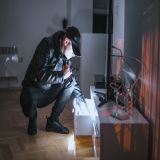 Mann mit Taschenlampe durchsucht Schublade