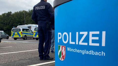 Rechts steht ein Blauer Stehtisch mit dem Logo der Polizei Mönchengladbach. Links sieht man einen uniformierten Polizisten von hinten. Auf dem Rücken die Aufschrift "Polizei".