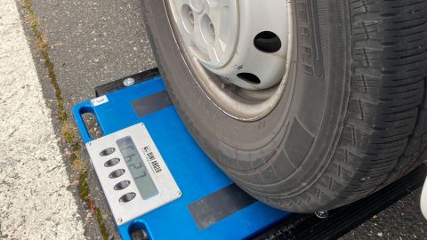 Der Reifen eines Wohnmobils steht auf einer Waage für Fahrzeuge. Auf dem Display der Waage wird das Gewicht angezeigt. 