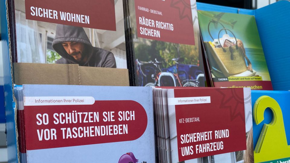 In einem kleinen Aufsteller sieht man sechs verschiedene Flyer-Sorten zu dem Thema Einbruchsschutz und Sicher im Urlaub. 