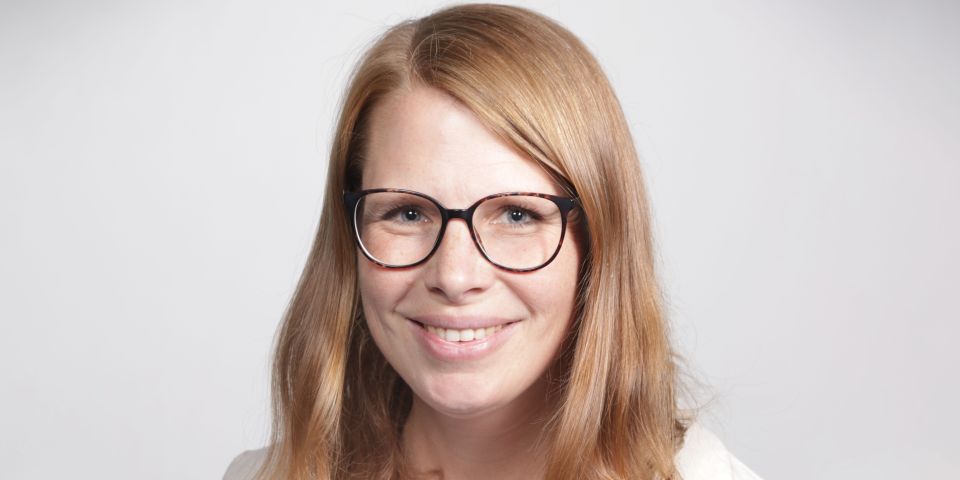 Stefanie Schilling, eine dunkelblonde Frau mit hellem Hautton, einer Brille mit schwarzem Rahmen und einer weißen Bluse mit einem beigen Blazer. 